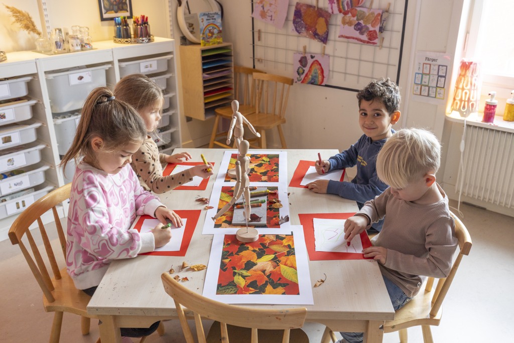Fyra barn ritar höstlöv i inspirerande innemiljö på förskolan Borgen i Sköndal.
