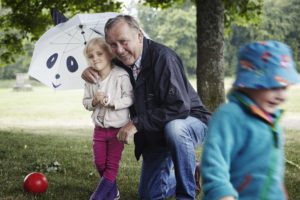 Äldre man med barn under paraply