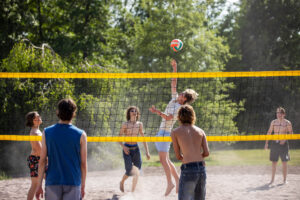 Ungdomar spelar beachvolleyboll.
