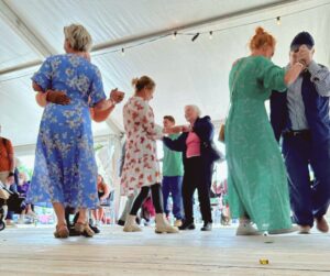 Finklädd personal och boende dansar i ett tält.