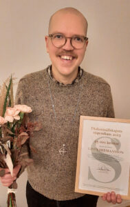 Diakon Linus Hermansson med blommor och inramat stipendiediplom.