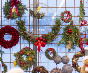 Julkransar och annat pynt fästa på galler på väggen. Till försäljning på Stora Sköndals julmarknad.